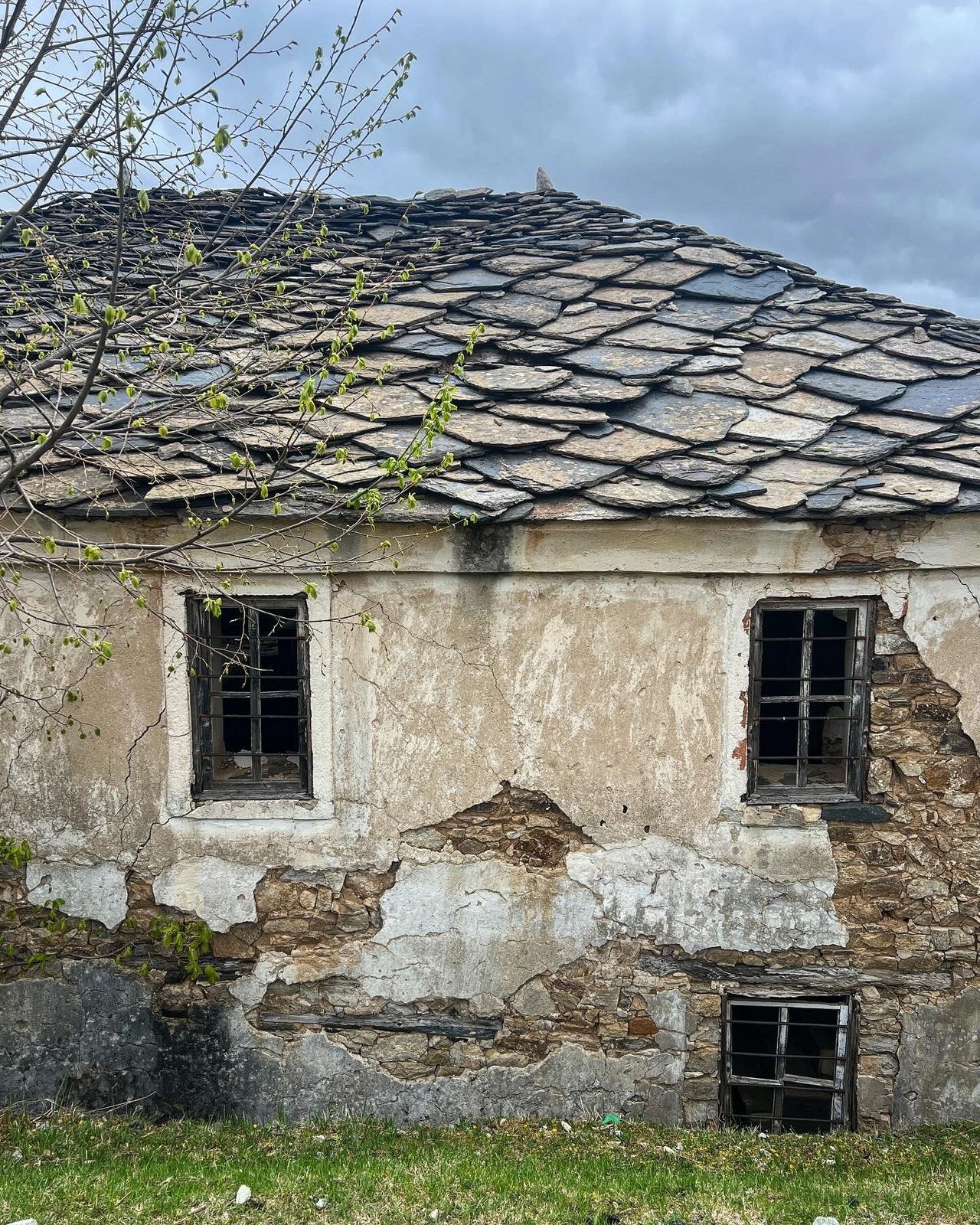 An abandoned stone house with a slate-tiled roof
