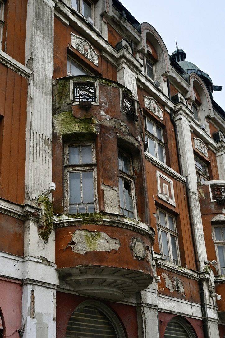 Crumbling balconies and moss on an old ornate facade