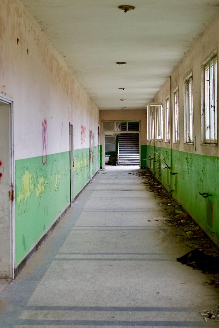 A long school corridor with green walls and graffiti